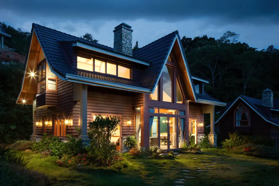 A craftsman house at dusk with the porch light on.