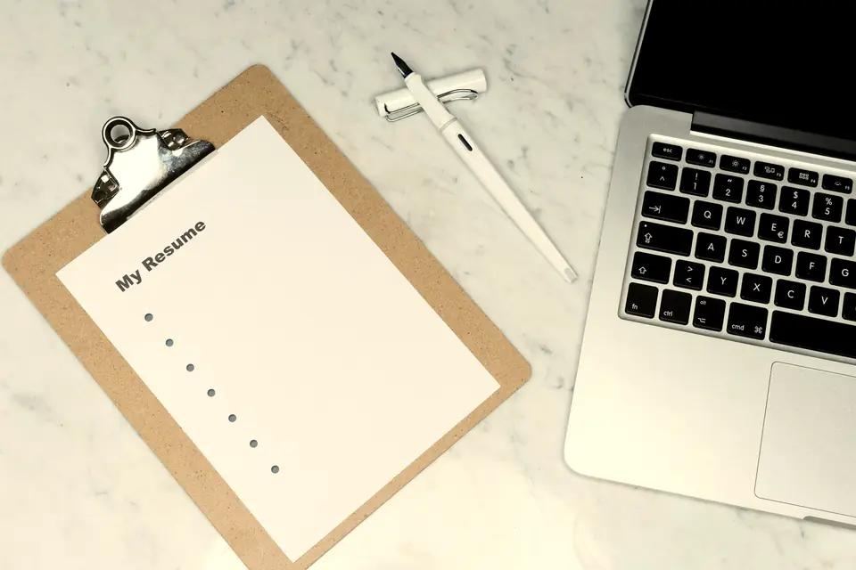 Two hands holding the edge of a printed document on a wooden desk.